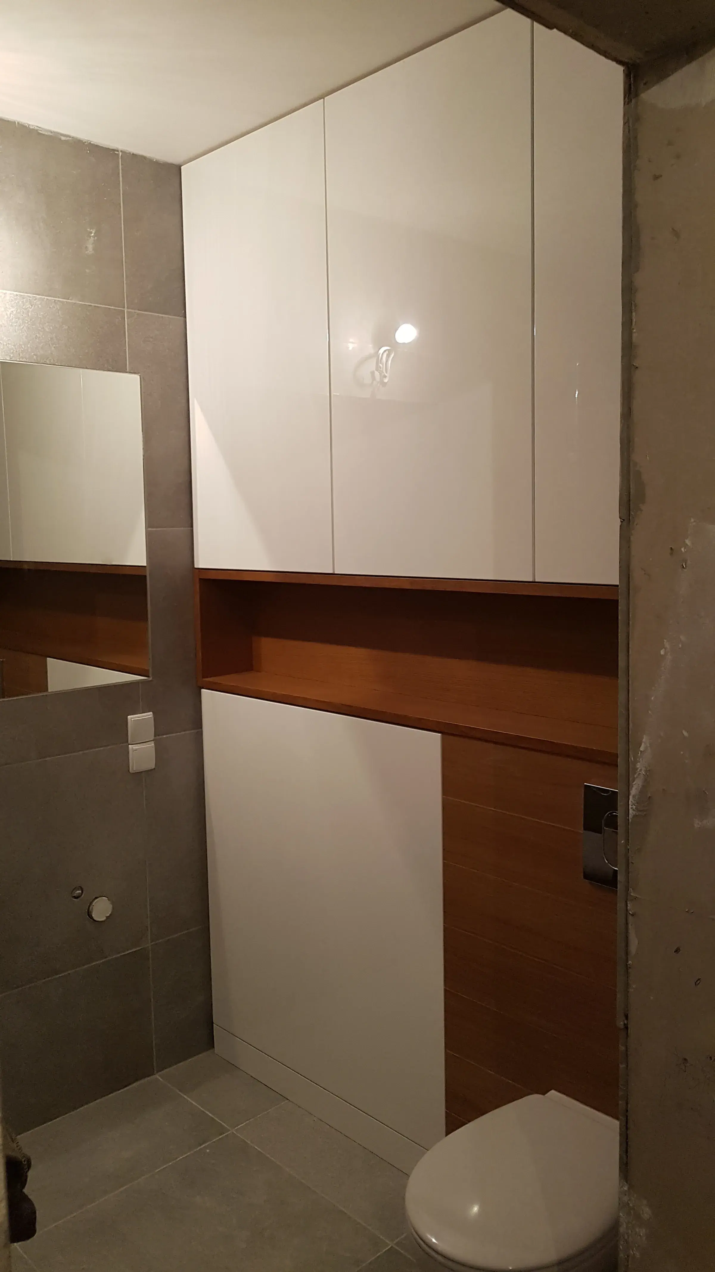 Zabudowa łazienki nad WC z orzechową półką